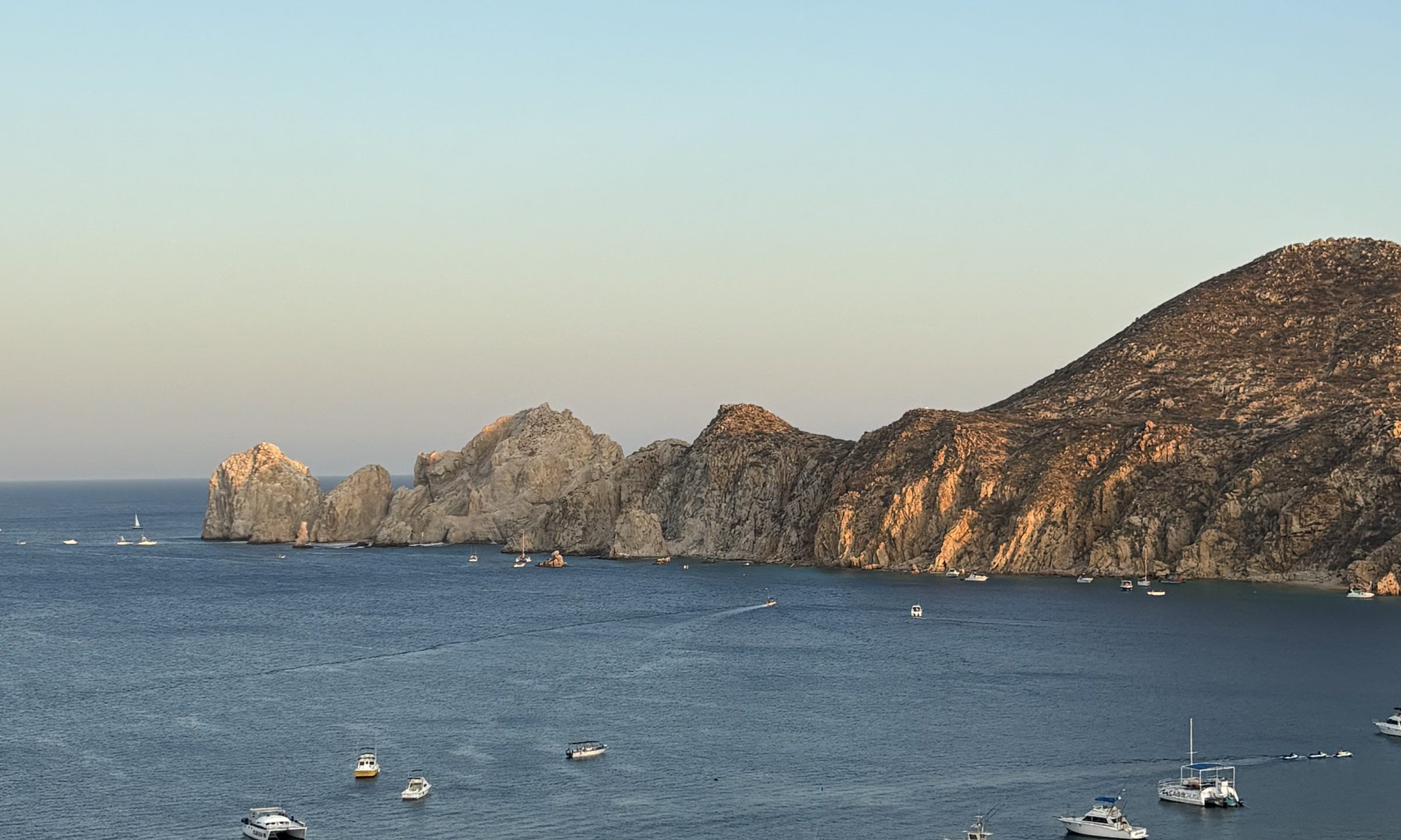 Cabo San Lucas bay at golden hour, the arch and the anchored fleet
